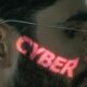 A close-up of a man's face illuminated by glowing green cyber text reflecting across his skin, symbolizing cybersecurity and digital interfaces.