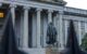 The statue of Albert Gallatin in front of the neoclassical Treasury Building in Washington, D.C., featuring grand columns and historic architecture.