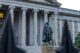 The statue of Albert Gallatin in front of the neoclassical Treasury Building in Washington, D.C., featuring grand columns and historic architecture.