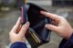A person examining an empty wallet, representing credit score challenges and financial struggles.