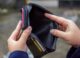 A person examining an empty wallet, representing credit score challenges and financial struggles.